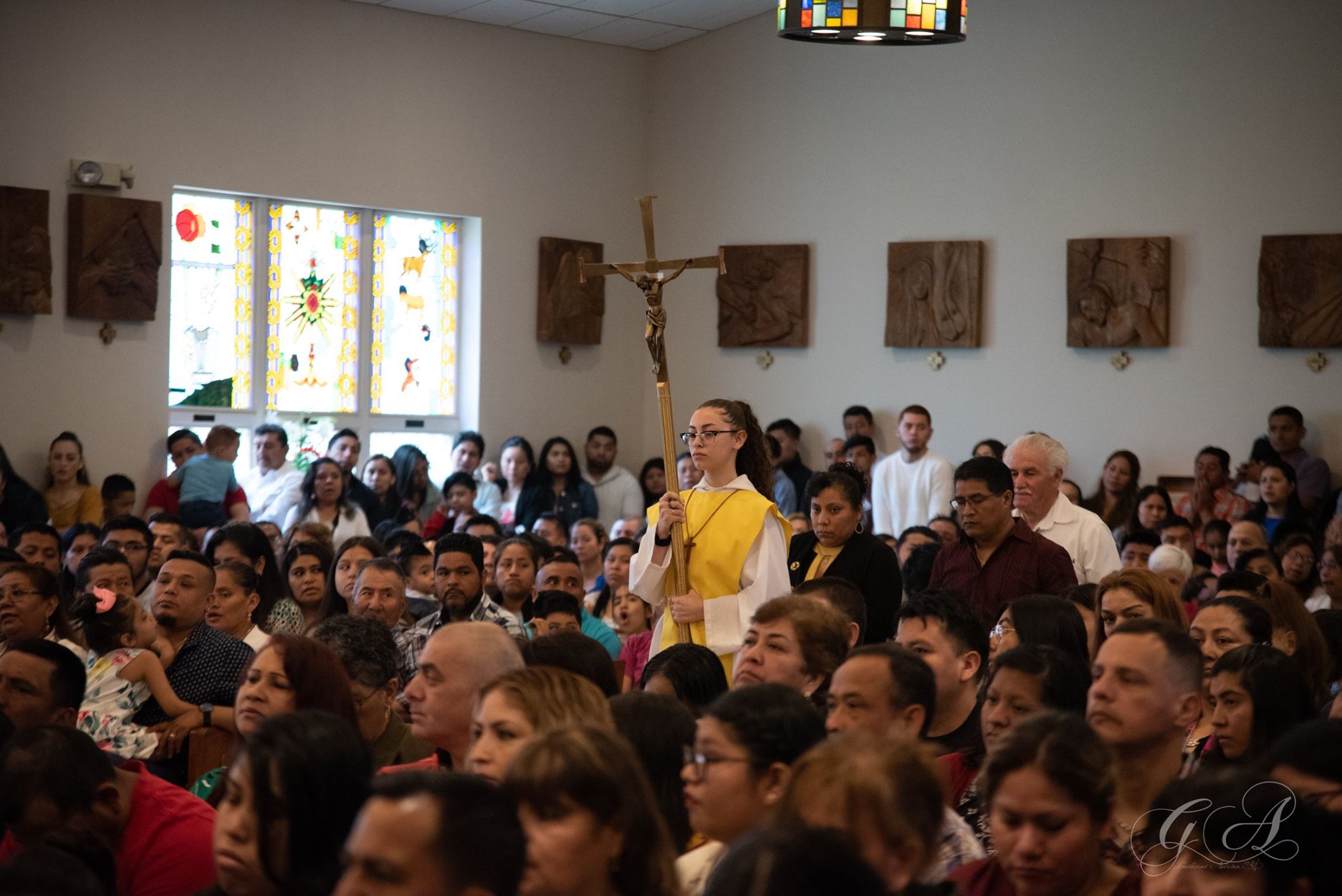Zdjęcie ministranta idącego nawą, niosąc krzyż.